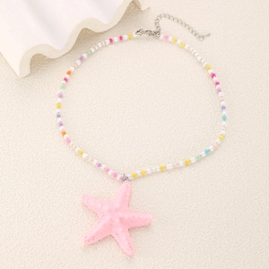 Gros plan du pendentif étoile de mer rose sur collier de perles avec fermoir mousqueton