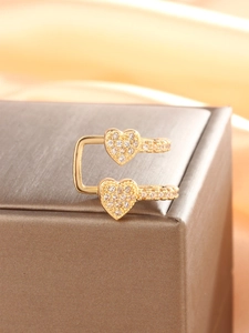 Detailansicht goldener herzförmiger Ohrklemmen mit Zirkonia-Mikropavé auf einer Schmuckbox