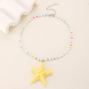 Détail d'un collier de perles colorées avec pendentif étoile de mer jaune et chaînette