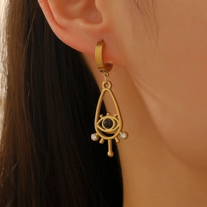 Détail de la boucle d'oreille œil protecteur dorée avec perle noire et zircon sur l'oreille