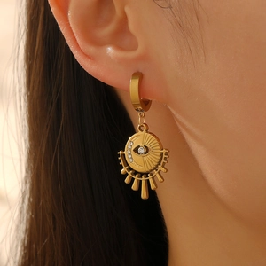 Gros plan d'une boucle d'oreille créole en acier doré avec pendentif œil solaire