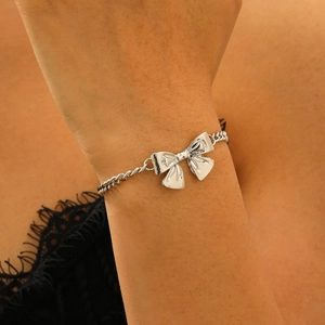 Nahaufnahme eines eleganten Silberarmbands mit Schleifenanhänger am Handgelenk