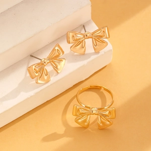 Detailansicht der eleganten goldenen Schleifen-Ohrstecker und des verstellbaren Rings