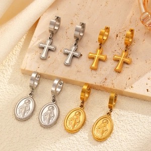 Détails des boucles d'oreilles religieuses en acier avec croix et médaille sur fond de satin