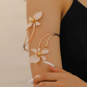Detail view of adjustable gold flower arm cuff with pink enamel petals on female model