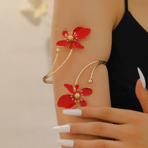 Detail view of gold flower arm cuff with red enamel petals on a model's upper arm