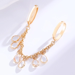 Detailed view of golden cuff earring with crystal tassel chain and teardrop zircon accents