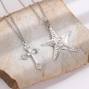 Vintage silver gothic cross and starfish layered necklace on textured stone base