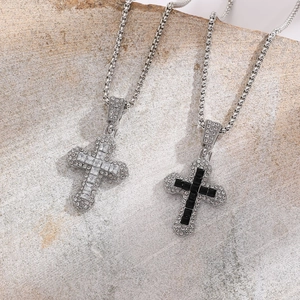 Close-up of black and white cross pendants with micro-pave crystals on stone background