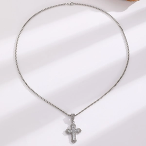 Detail of silver cross pendant with sparkling zircons on layered beaded necklace chain