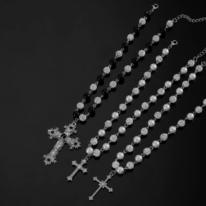 Detailed close-up of dark gothic beaded necklaces with vintage cross pendants and pearls