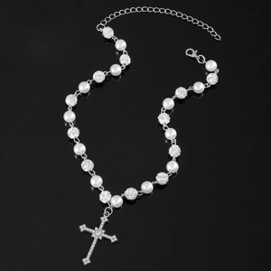 Close-up of gothic cross pendant necklace with rhinestones and white pearls