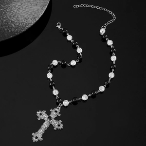 Detail of gothic cross necklace with carved patterns, beads, and lobster clasp closure