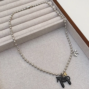 Detail der Kugelhalskette mit schwarzem Pferdehänger und Goldstern auf Samttablett