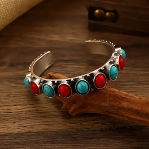 Macro detail of Bohemian open cuff bracelet with turquoise and red stones on wood