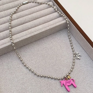 Nahaufnahme von rosa Emaille-Pferd-Anhänger und Perlenkette in einer Schmuckschatulle