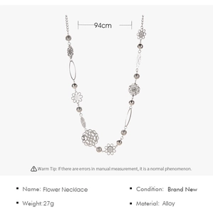 Détail du collier long en alliage argenté avec fleurs ajourées et perles polies