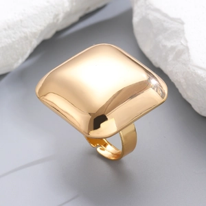Macro detail of chunky square geometric open ring with glossy golden metallic finish