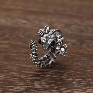 Macro detail of gothic silver lizard ring featuring intricate scales and black stone eyes