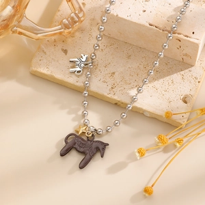 Nahaufnahme von Emaille-Pony und Goldstern-Anhängern an einer silbernen Perlenkette