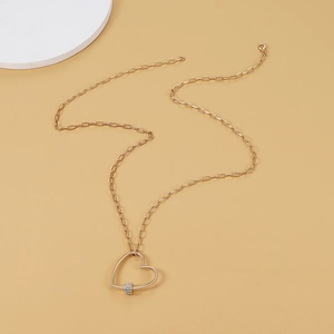 Détail d'un pendentif cœur doré avec pavé de cristaux sur une chaîne à trombones