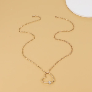 Vue détaillée d'un pendentif cœur doré avec strass brillants et une fine chaîne à maillons