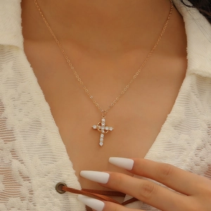Detail of gold cross and crescent pendant with white zircons on a model wearing lace