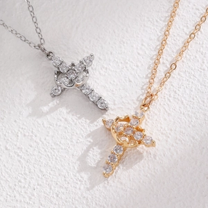 Close-up of crown cross necklaces with inlaid zircons in gold and silver finishes