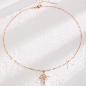 Close-up of gold crown cross necklace with sparkling rhinestones and lobster clasp