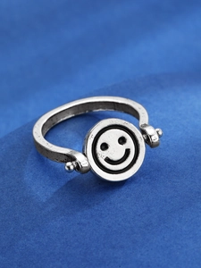 Dettaglio macro di anello rotante vintage con disco a faccina sorridente e finitura anticata