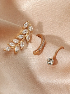 Detail view of gold leaf zircon ear cuffs and pavé hoop on champagne silk fabric
