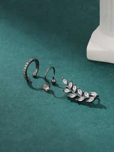 Detail of three-piece gunmetal ear cuff set with marquise stones on a green surface