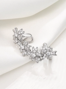 Detail of silver ear cuff with five sparkling floral zircon patterns on silk background