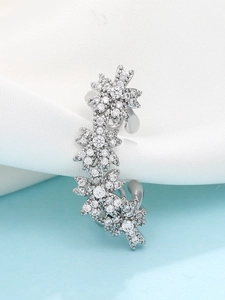 Macro view of floral micro-set zircon ear cuff on white silk and blue background
