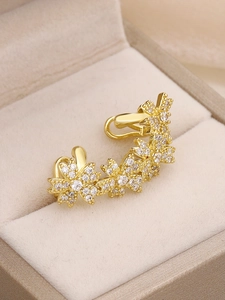 Macro detail of gold flower ear cuff with micro-pasted cubic zirconia in jewelry box