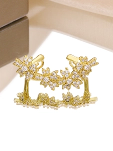 Detailed macro view of gold-plated flower ear cuff with micro-paved cubic zirconia stones