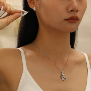 Close-up of MOM LOVE stainless steel necklace and earrings set worn by a model