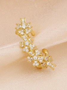 Close-up of three gold floral ear cuffs with micro-pave cubic zirconia on silk fabric