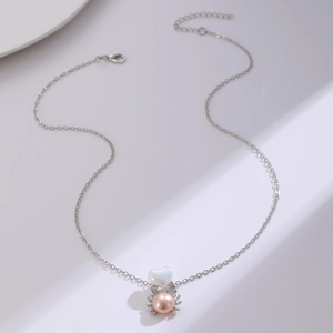 Detalle del colgante de ópalo en forma de corazón y perla rosa en cadena de plata
