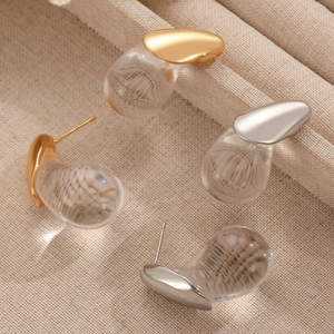 Macro shot of minimalist teardrop earrings with gold and silver polished metal accents