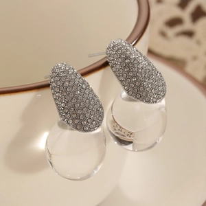 Close-up of teardrop earrings with silver metal pavé rhinestones and clear resin pendants