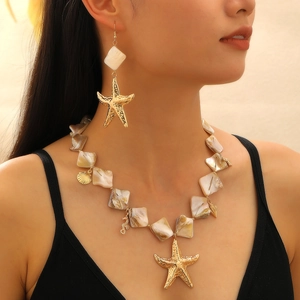 Dettaglio di un set collana da spiaggia con stelle marine dorate, conchiglie e perle