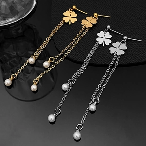 Detalle de pendientes de trébol de cuatro hojas con borlas largas de oro y plata