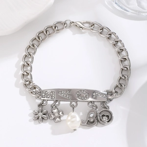 Macro detail of silver charm bracelet featuring pearl, heart pendants and HKOL crystal tag