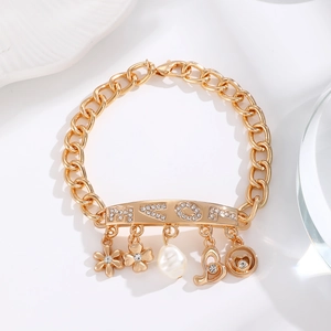 Close-up of gold chain bracelet with MEOY letter plate, floral charms and pearl
