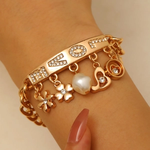 Detail of gold chain bracelet featuring rhinestone LOVE letters and heart pearl charms