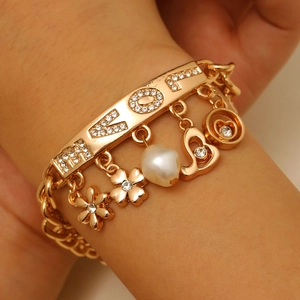 Detailed close-up of golden LOVE letter bracelet with rhinestone heart and flower charms