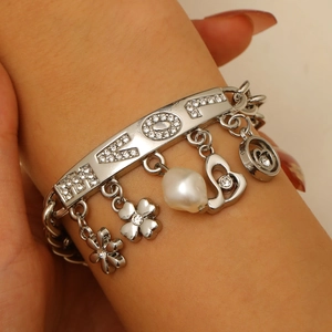 Close-up of a silver charm bracelet with LOVE rhinestones, heart and baroque pearl charms
