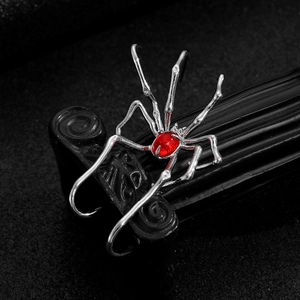 Gothic silver spider ear cuff with a large red gemstone on a vintage black stand
