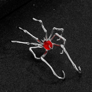 Macro shot of silver spider ear cuff with a vibrant red gemstone on black background